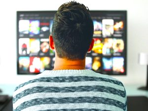 The image shows a man watching TV.